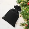 Bolsas de terciopelo negro para regalos de Navidad con ramas de abeto.